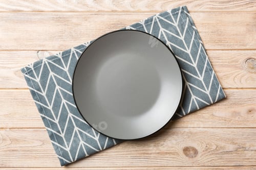 Preview: Top view on colored background empty round gray plate on tablecloth for food.