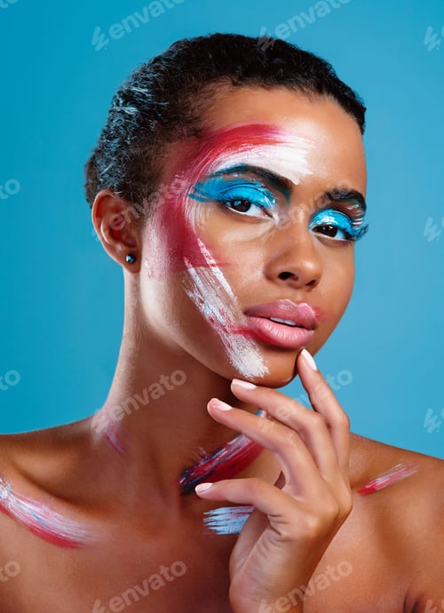Preview: Studio portrait of a beautiful young woman covered in face paint posing against a blue background