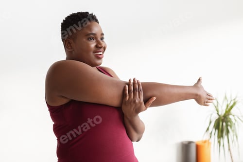 Preview: Poisitive plus size black woman doing stretching at studio