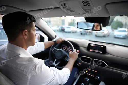 Preview: Man driving his modern luxury car, view from backseat
