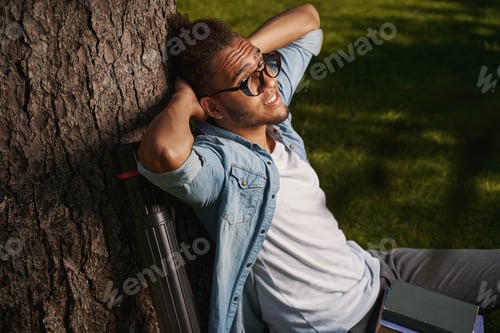 Preview: Relaxed young man in casual clothes sitting outdoors