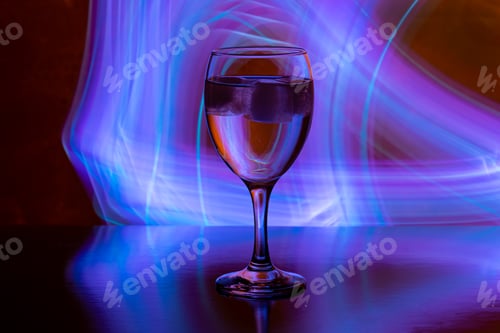 Preview: wine glass with ice on black backgound with neon light painings behind