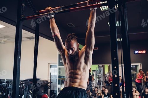 Preview: Young man training in gym, swinging on exercise bar