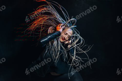 Vista previa: A beautiful girl listens to music with headphones on a black background waving her hair