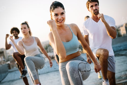 Preview: Group of happy fit friends exercising outdoor in city