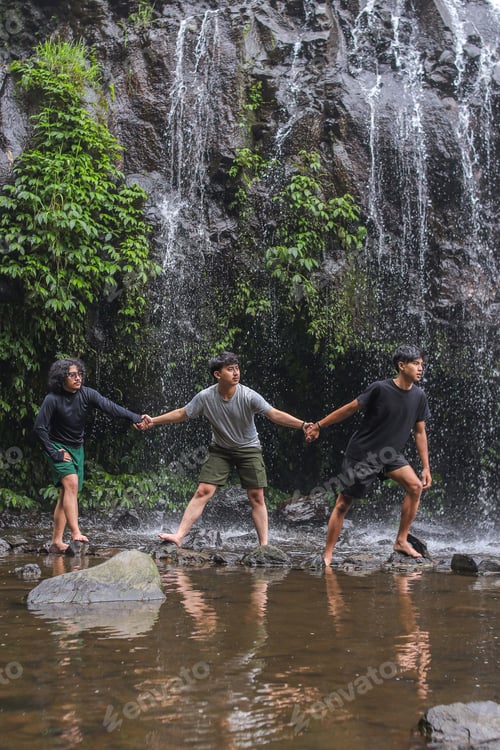 Preview: Three Young Men Joyfully Exploring Stunning Tropical Waterfall Together Holding Hands Barefoot