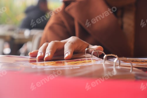 Preview: Hand reaching for a menu at a cafe on a sunny afternoon