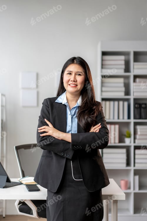 Preview: A woman in a business suit stands in front of a desk with a laptop