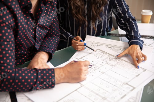 Preview: Close up with the hands of two architects discussing some dimensions of a project