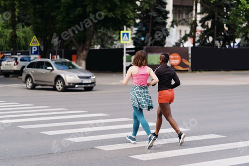 Preview: Two multiethnic girls running through the city streets, outdoor communicating