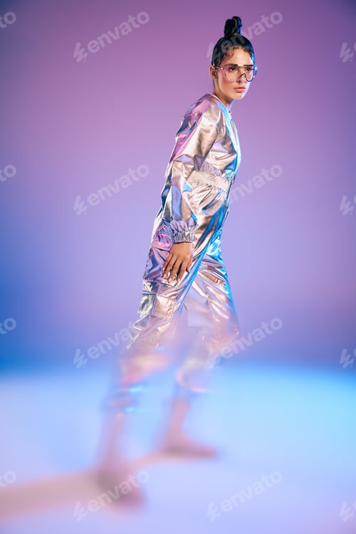 Preview: Stylish young woman in futuristic holographic attire showcases modern fashion trends