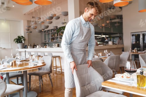 Preview: Handsome male waiter in apron working in restaurant