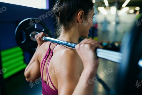 Preview: Athletic woman in gym lifting weights at the gym
