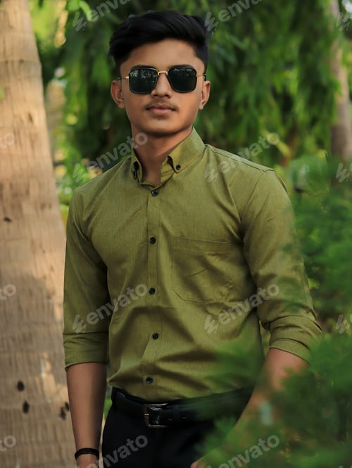 Preview: Young Indian male with olive green shirt and black sunglasses posing in the garden