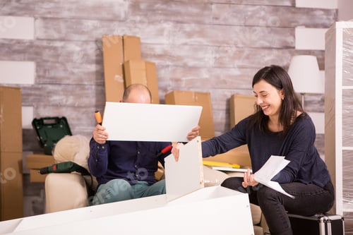 Preview: Couple working as a team to assemble furniture in new apartment