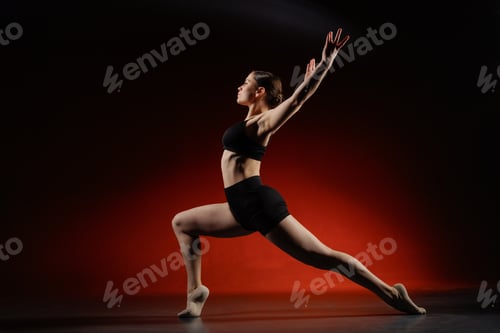 Preview: Athletic woman stretching in lunge pose in studio, red background copy space