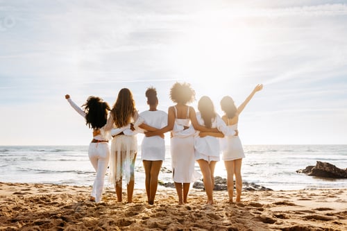 Preview: Bride's team. Back view of group of young diverse women posing and embracing by the seashore. Hen