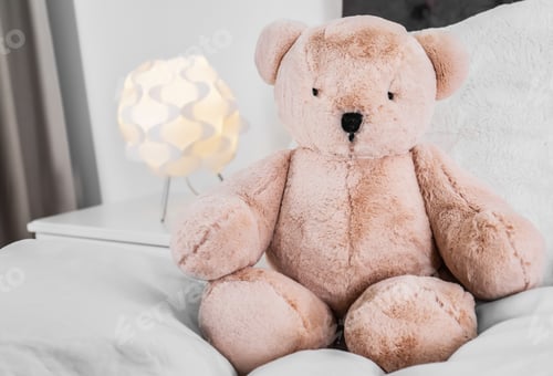 Preview: Cute teddy bear sitting on bed indoors. Space for text