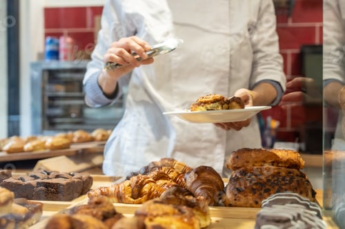 Preview: Chef serving fresh pastry to customer in bakery