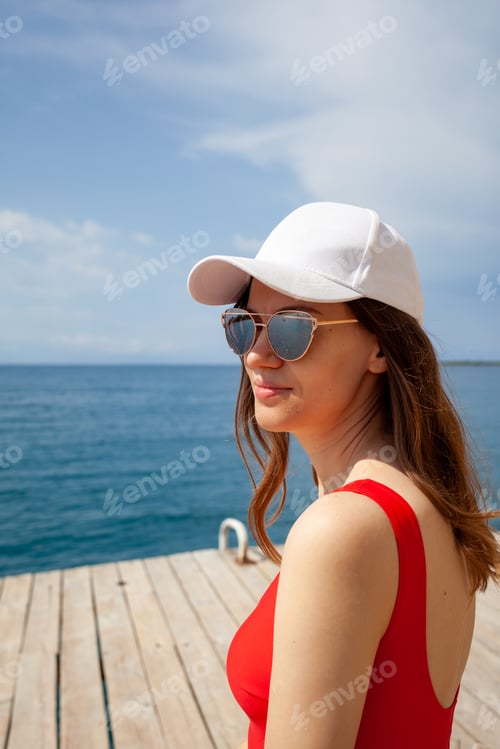 Preview: A beautiful girl with long hair and a white cap looks at the blue sea
