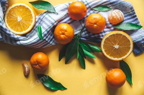Preview: Fresh clementines, oranges on board with green leaves with a knife. Top view on a yellow background