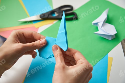 Preview: DIY concept. Woman make origami easter rabbit from color paper. Origami lessons