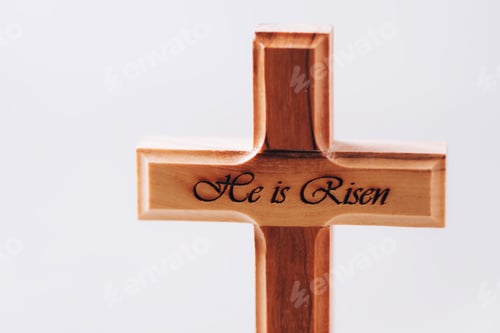 Preview: Wooden cross with text He is risen on grey background. Reminder of Jesus sacrifice and Christ