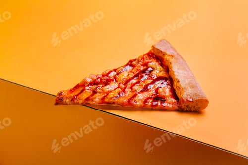 Preview: Slice of pizza resting on a vibrant orange surface showcasing melted cheese and toppings during
