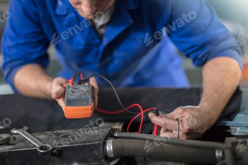 Preview: Mechanic using a multimeter on a vehicle.
