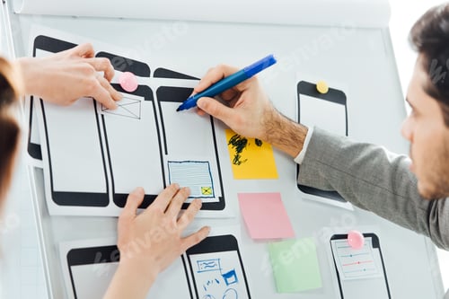 Preview: Selective focus of developers with marker working with wireframe sketches for mobile website on