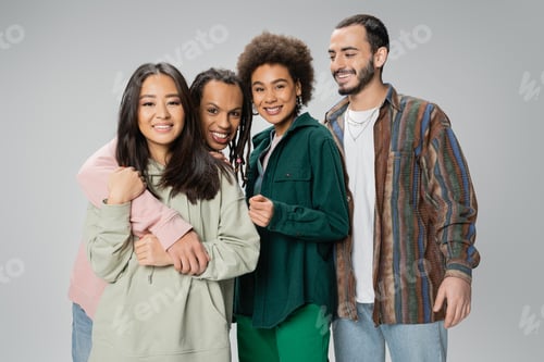 Preview: trendy multiracial man with dreadlocks embracing asian woman and smiling at camera near happy