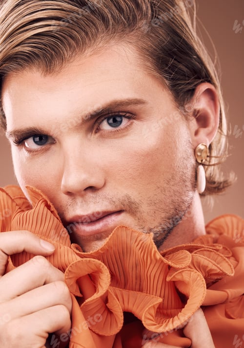 Preview: Lgbtq, fashion and portrait of man with makeup, beauty and creative orange clothes on studio backgr