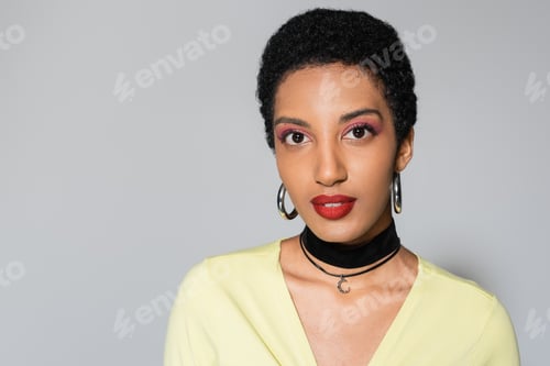 Preview: Portrait of pretty african american model with bright makeup looking at camera on grey background