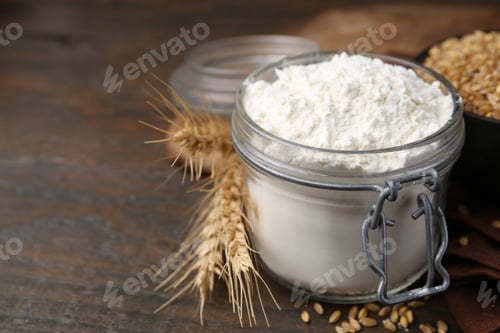 Preview: Wheat flour, grain and spikes on wooden table, closeup. Space for text