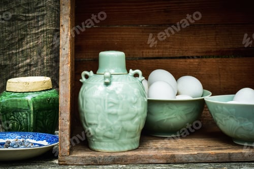 Preview: Celadon green glazed ceramic bottle and bowls filled with raw white eggs