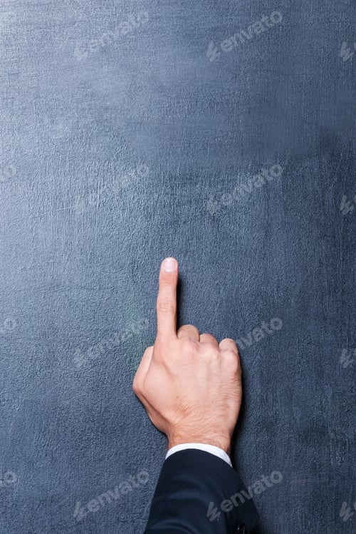 Preview: Look up! Close-up of human hand pointing copy space against blackboard