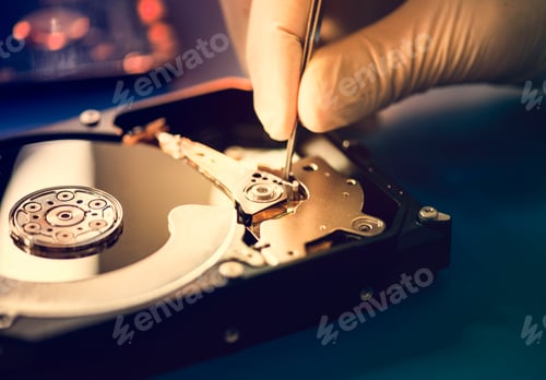 Preview: Closeup of hands with tweezers and computer hard disk