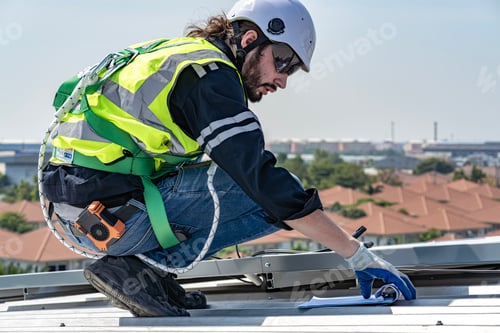 Preview: Male engineer installing or checking the working condition of solar panels on the roof