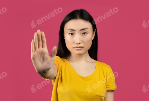 Preview: Young japanese lady gesturing STOP, showing rejection gesture, expressing her negative attitude