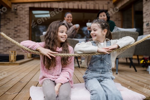 Preview: Two happy sisters with mother and grandmother sitting outdoors in patio in autumn