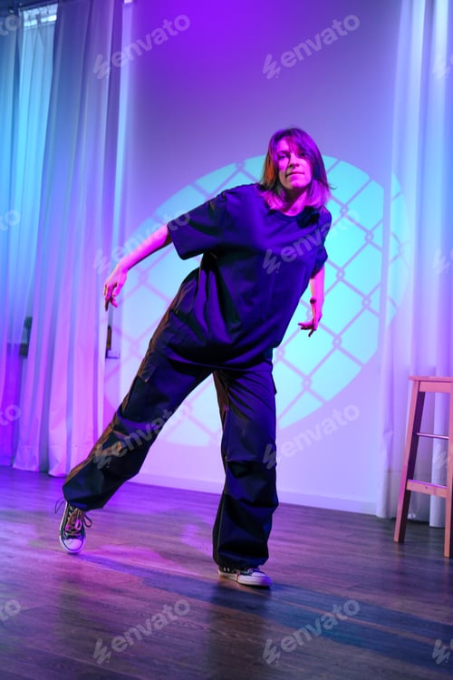 Preview: Dancer performs expressive routine in dimly lit studio with colorful lighting during evening session