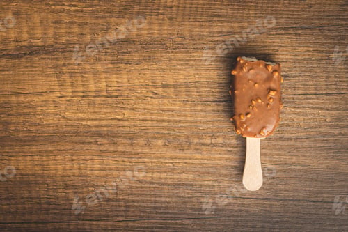 Preview: Popsicle, ice cream covered with chocolate on wooden table. Top view.