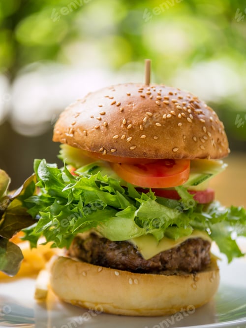 Preview: Classic deluxe cheeseburger with lettuce, onions, tomato and pickles on a sesame seed bun.