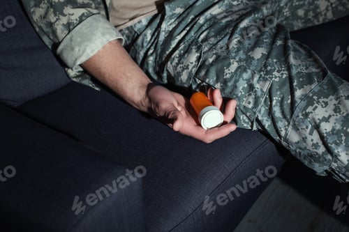 Preview: Cropped view of soldier with ptsd holding pills on couch at home