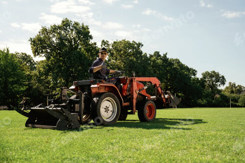 Preview: Man is with utility tractor with grass cutter and aerator equipment on the field
