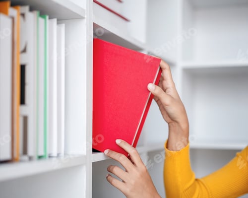 Preview: A person is reaching for a red book on a shelf