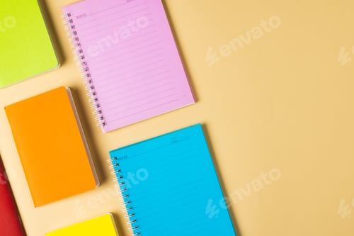 Preview: Composition of colorful notebooks lying on yellow surface with copy space