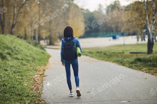 Preview: A brunette girl with a bag on her back goes to the Park to make sports.