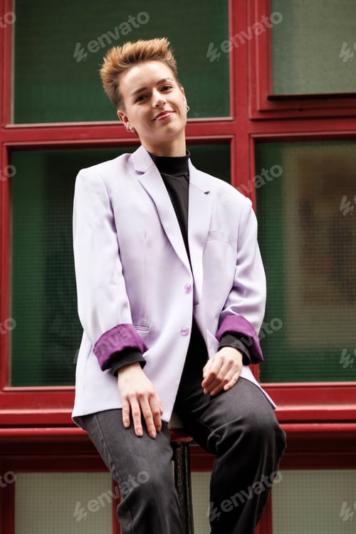 Preview: Alternative female model sitting on street bollard looking relaxed.