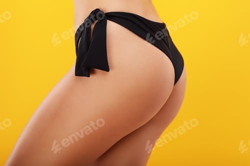 Preview: Sexy woman in bikini posing against yellow background